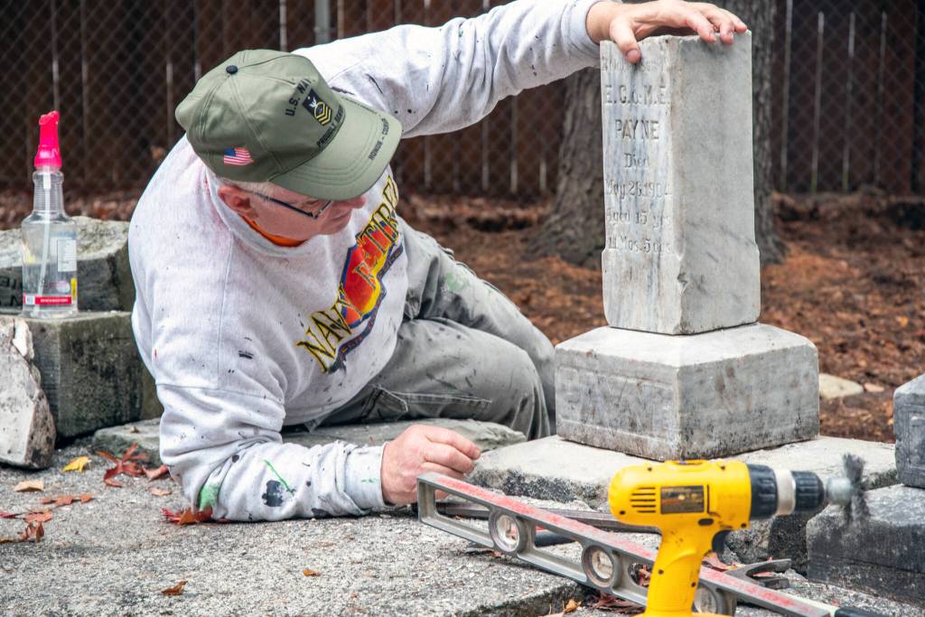 Marion Mick Hersey checks the placement of the headstone of the 15-year-old son of E.C. and M.E. Payne. Hersey is a National Historical Preservationist and Navy veteran from Kitsap County, who came to Sequim to help members of the Sequim Prairie Garden Club and other volunteers repair headstones in the Pioneer Memorial Park. Sequim Gazette photo by Emily Matthiessen
