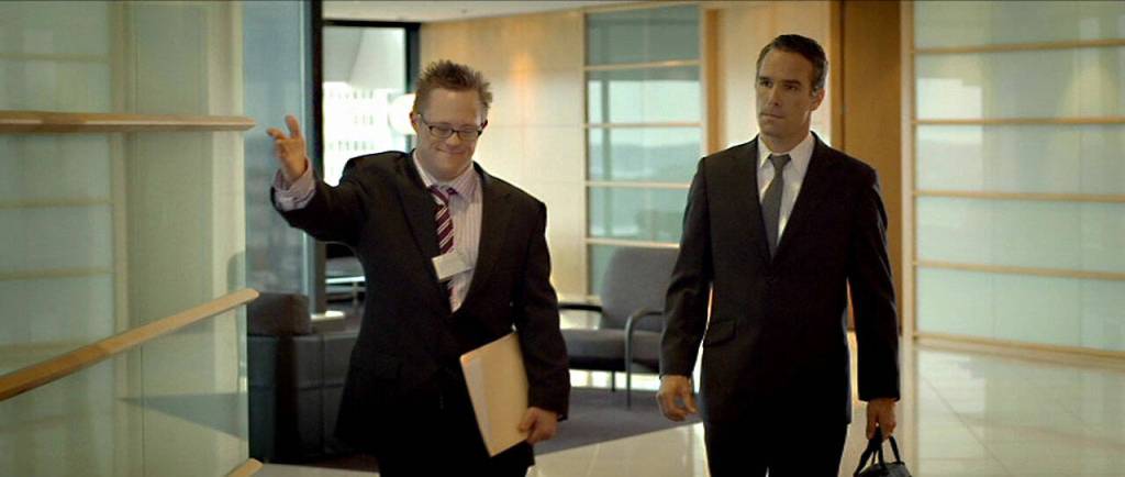 In the film The Interviewer, James Dexter (portrayed by Gerard Odwyer) ushers an unsure Thomas Howell (portrayed by Winston Cooper) into a meeting room to conduct a job interview. Screenshot courtesy of Sproutflix