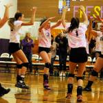 Sequim High volleyball teammates celebrate a key point in a 2015 match as head coach Jennie Webber Heilman (background, left) looks on.