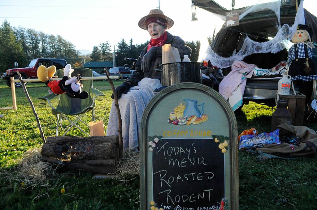 Bob Clark helps hand out candy at the Sequim Prairie Granges drive-through event Oct. 30 while roasting up a morbid meal. See more Halloween photos, A-8. Sequim Gazette photo by Matthew Nash