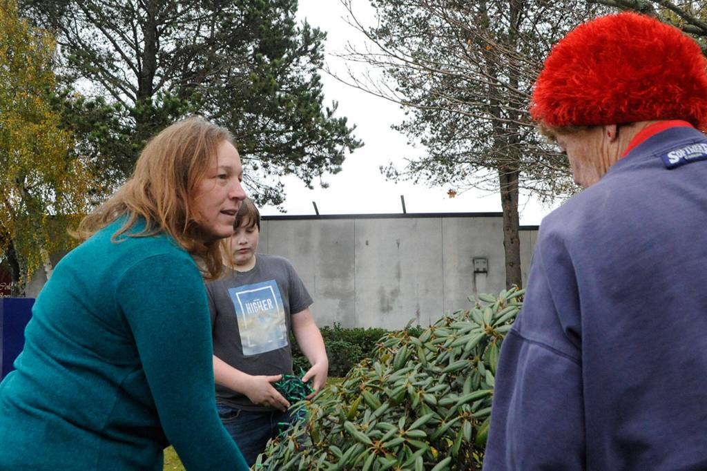 Susan Baritelle and her son Brayden, 10, work with Emily Westcott to wrap lights around trees and bushes in downtown Sequim. Sequim Gazette photo by Matthew Nash