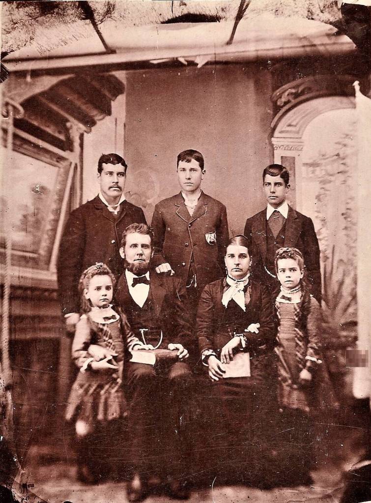 The headstone of Moore Waldron can be found in Sequims Pioneer Memorial Park. A photograph of Moore with his wife and five children was taken in 1880 and shared by Cheryl England, whose husband is a descendant of Frank Moore, standing on the far left. Photograph courtesy of the England family