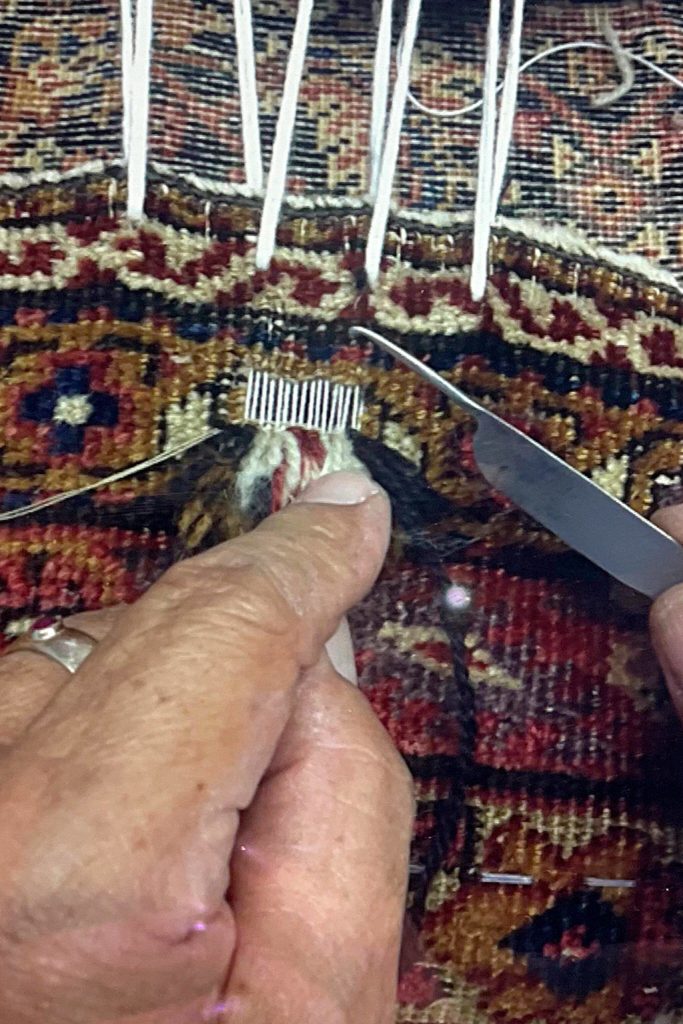 Mohammad Amin Rahmati, owner of Oriental Rug Care, started to learn from his father how to repair rugs at age 13 and almost 60 years later he continues the tradition in his Sequim shop. Here he intricately repairs a rug to make it appear as if no damage had been done. Photo courtesy of the Rahmati family