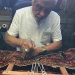 Mohammad Amin Rahmati, owner of Oriental Rug Care, started to learn from his father how to repair rugs at age 13 and almost 60 years later he continues the tradition in his Sequim shop. Here he intricately repairs a rug to make it appear as if no damage had been done. Photo courtesy of the Rahmati family