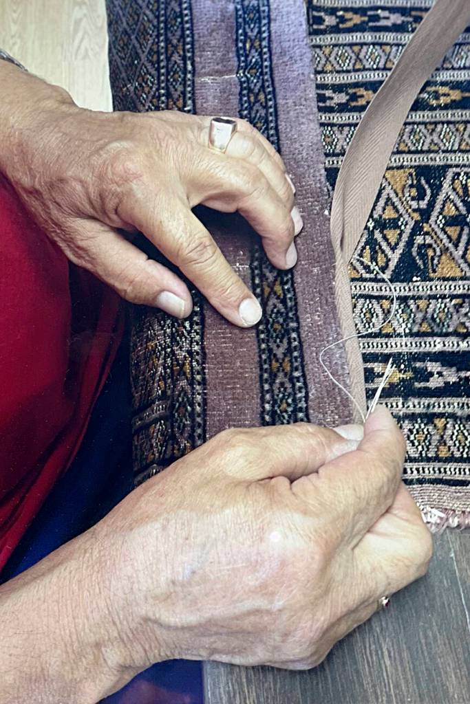 Mohammad Amin Rahmati, owner of Oriental Rug Care, started to learn from his father how to repair rugs at age 13 and almost 60 years later he continues the tradition in his Sequim shop. Here he intricately repairs a rug to make it appear as if no damage had been done. Photo courtesy of the Rahmati family