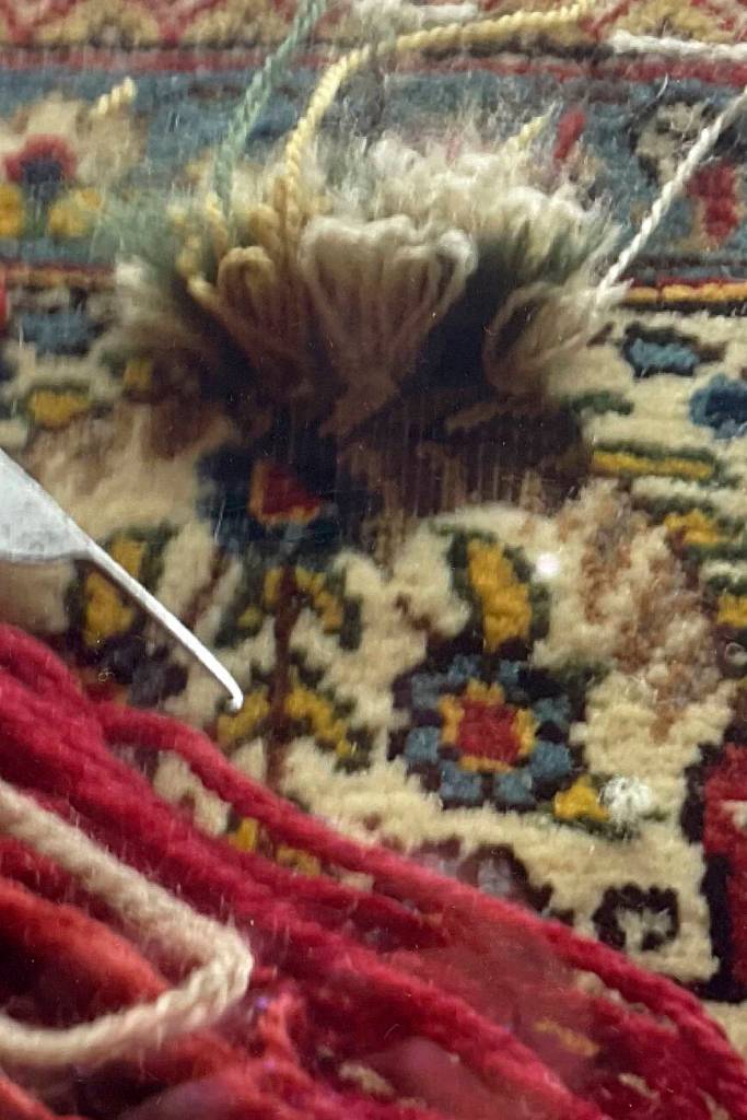 Mohammad Amin Rahmati, owner of Oriental Rug Care, started to learn from his father how to repair rugs at age 13 and almost 60 years later he continues the tradition in his Sequim shop. Here he intricately repairs a rug to make it appear as if no damage had been done. Photo courtesy of the Rahmati family