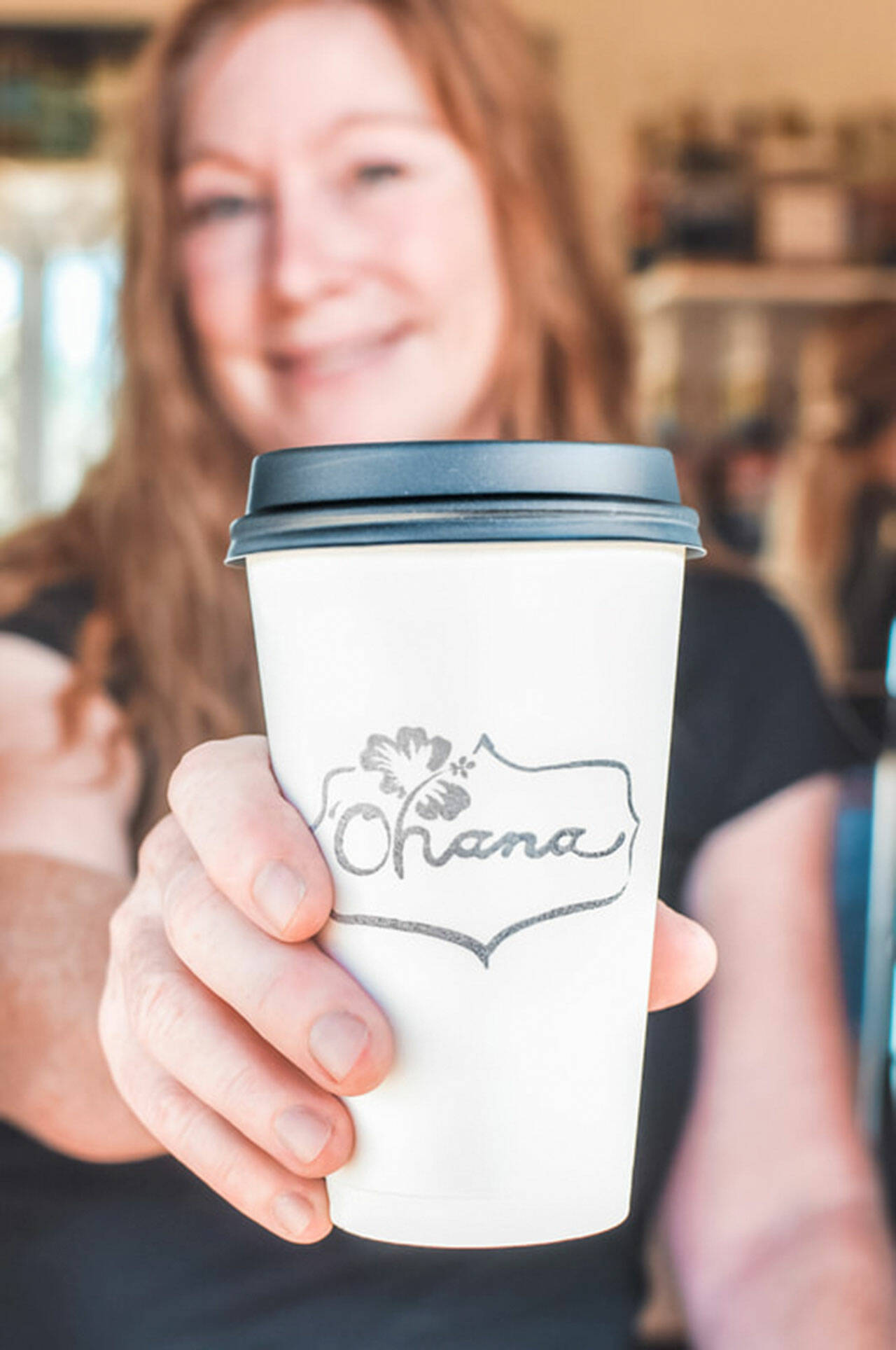 Owner Lori Gray holds out an Ohana coffee cup. Photo courtesy of Ohana by Kelsey Horst