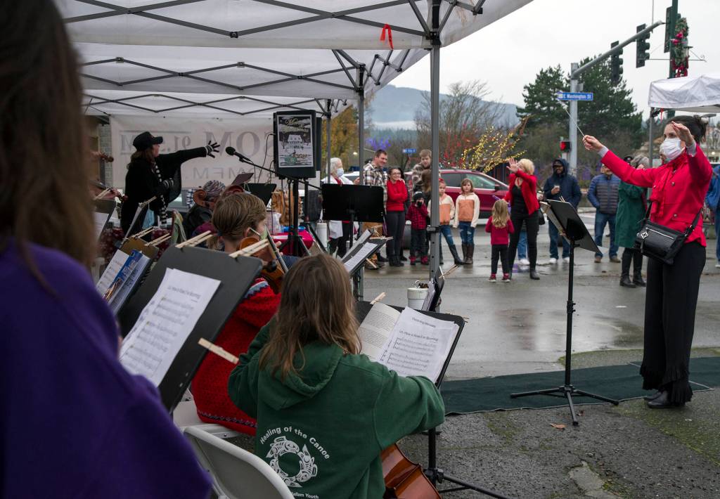 Teresa Herman leads young members of the Sequim City Orchestras Strings Program in a performance of classic holiday music as Santa meets members of the crowd at Home Town Holidays. Sequim Gazette photo by Emily Matthiessen