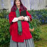 Karla Morgan, who says she loves historical re-enacting smiles in front of holiday lights in downtown Sequim during the Home Town Holidays event. She said the clothes resemble those worn by women in early to late Civil War times. No hoops, though, she said  too hard to drive in. Sequim Gazette photo by Emily Matthiessen