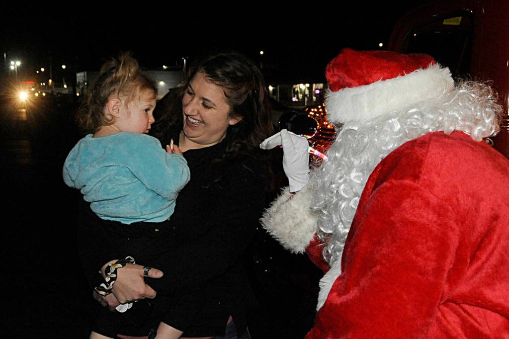 Morgan Snell holds her niece Remi Rigg, 2, after meeting Santa Claus and receiving a candy cane while stopping at the Santa Brigade at the Sequim Village Shopping Center on Dec. 9. Sequim Gazette photo by Matthew Nash