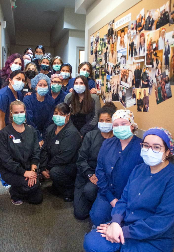 Some of the 27 member staff at Northwest Eye Surgeons pose by a bulletin board full of images from good times with Dr. Matthew Niemeyer. Sequim Gazette photo by Emily Matthiessen