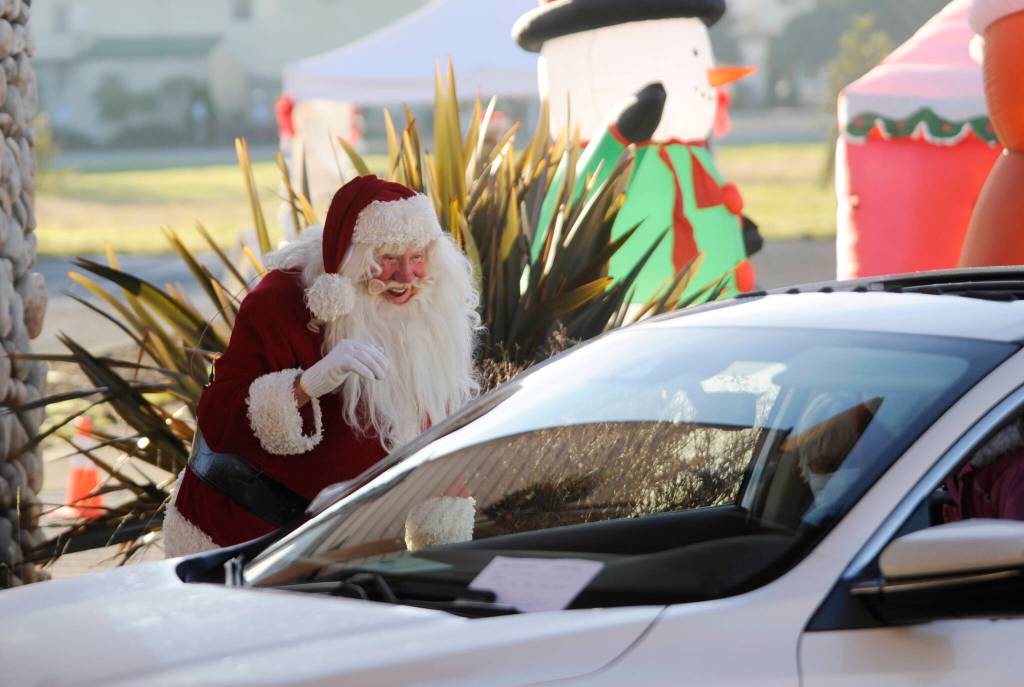 Santa Claus (Mac Macdonald) greets attendees of the Say Hello to Santa drive-by event on at Dungeness Valley Lutheran Church in December 2020. Hosted by First Teacher and the Parenting Matters Foundation, the event saw youths receiving a goodie bag while spending a socially-distanced visit with Mr. Claus and his group of group of volunteer elves. Sequim Gazette file photo by Michael Dashiell