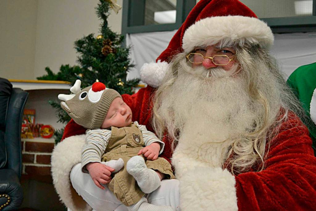 Santa Claus, aka George Stuber, holds a newborn baby at the Breakfast with Santa event in 2014. Sequim Gazette photo by Matthew Nash