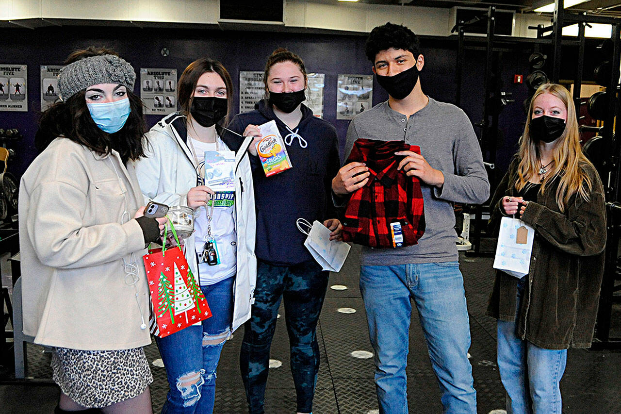 More than 400 Sequim High Schoolers received a gift of some sort last week as part of the Winter Wishes event that grants students wishes. From left, Alivia Gray, Jordan Kidd, Sammie Bacon, Sergio Arreguin, and Delaney Sisemore hold up their gifts during their home room on Dec. 15. Kidd received a gas card, and Arreguin a flannel shirt, and the other three got treats. Sequim Gazette photo by Matthew Nash