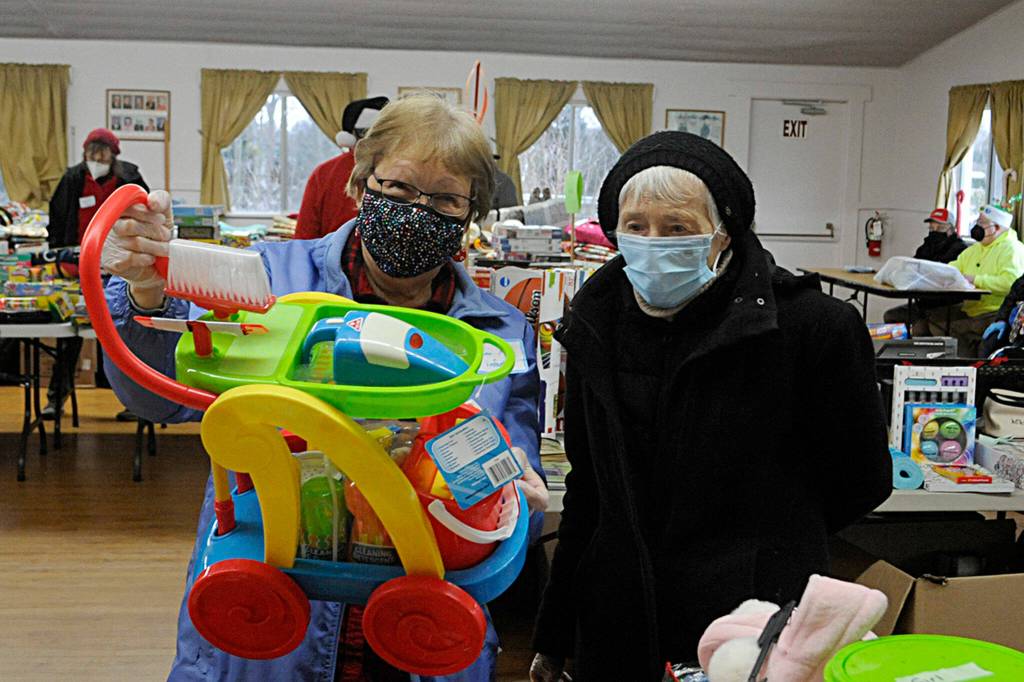 Alisha Whitley looks through the family movies at Toys for Sequim Kids on Dec. 15 with her helper elf Linda Reichl. Sequim Gazette photo by Matthew Nash