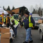 Several volunteer groups work together to load vehicles with food for the holidays during the Family Holiday Meal Bag program on Dec. 17 in Carrie Blake Community Park. Sequim Gazette photo by Matthew Nash