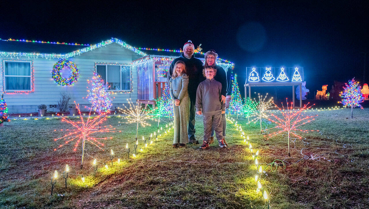 The Bixby family, Emma, Corey, Tennille and Colin stand in their yard which they have decorated with Christmas lights that are programmed to change with music. Sequim Gazette photo by Emily Matthiessen
