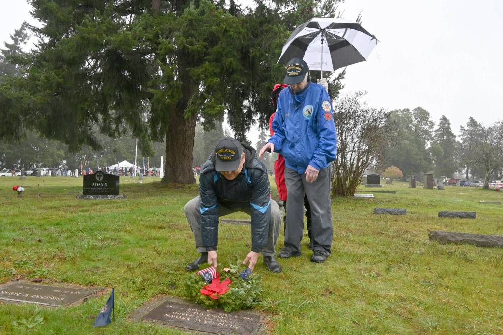 Third mate Russel Hammond, left, and Second Mate Bob Barbee, representing the U.S. Merchant Marines, lay a wreath on the grave marker of fellow Merchant Marine Olen Oral Brown at Sequim View Cemetery on Dec. 18.