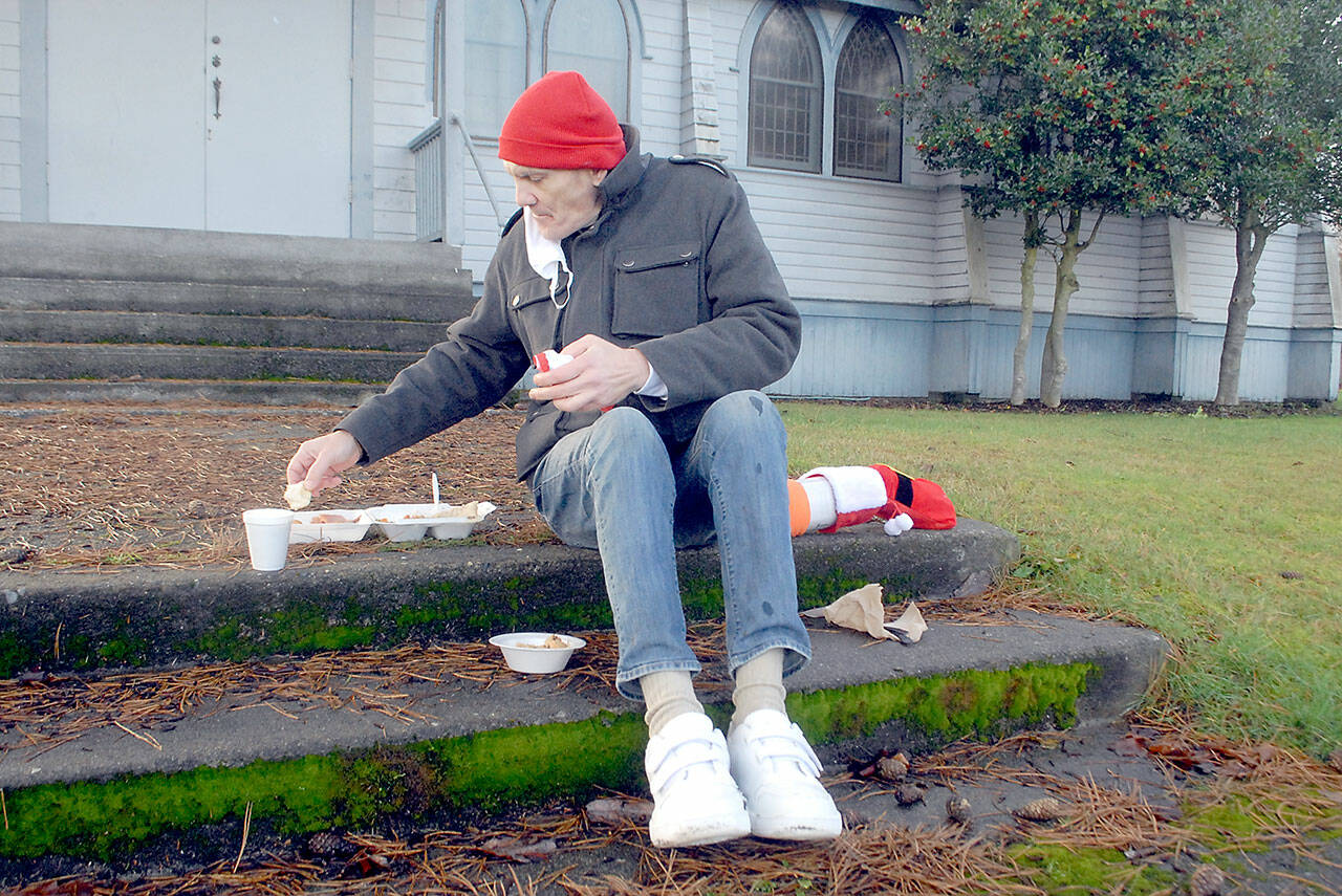 Photo by Keith Thorpe/Olympic Peninsula News Group
Michael Freestone of Port Angeles sits on the steps in front of the Salvation Army Church in Port Angeles as he enjoys a carry-out Christmas Eve lunch. The organization served dozens of lunches with an outdoor dining twist in its annual holiday tradition.