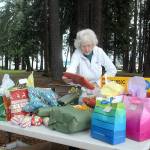 Keith Thorpe/Peninsula Daily News
Ingrid Carmean of Port Angeles, a member of Food Not Bombs, an international group dedicated to assisting and feeding homeless individuals, sets up a table filled with Christmas presents on Saturday at Jesse Webster Park in Port Angeles.  The presents, along with a hot lunch, were distributed to needy individuals on Christmas Day, one of the group's every-other-weekend community meals.