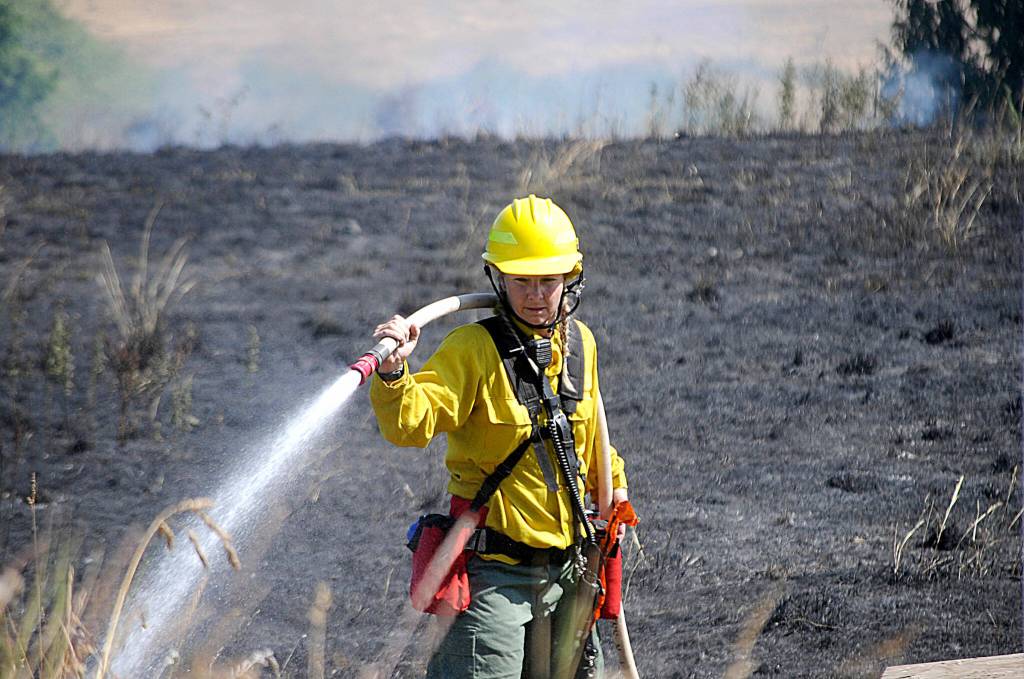 Firefighter/paramedic Margie Brueckner with Clallam County Fire District 2 looks for hot spots at a brush fire near Sherburne Road in July. Sequim Gazette photo by Matthew Nash