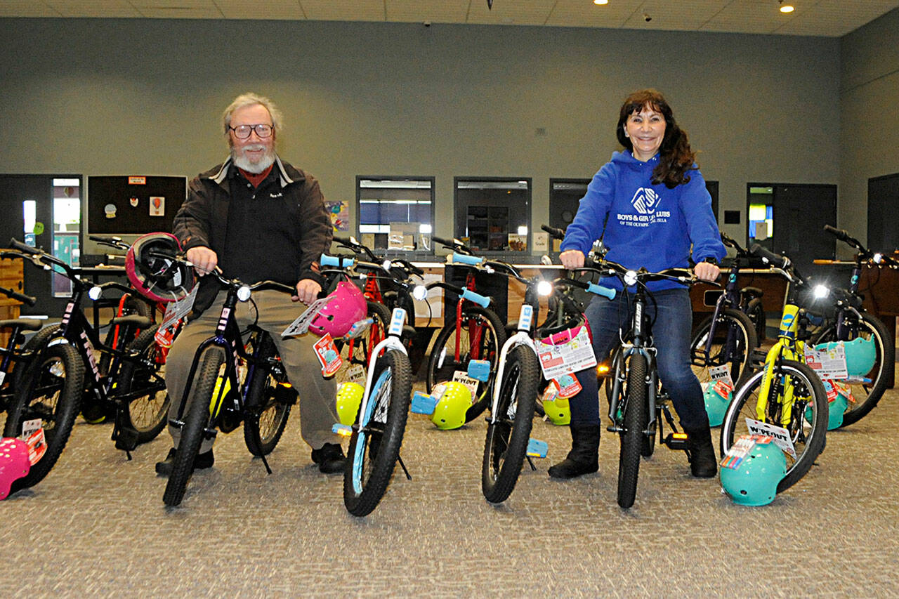 Sam Chandler, owner of Bens Bikes, and Mary Budke, executive director of the Boys & Girls Clubs of the Olympic Peninsula, sit on some new bikes Chandler donated for in-need club members in Sequim and Port Angeles.