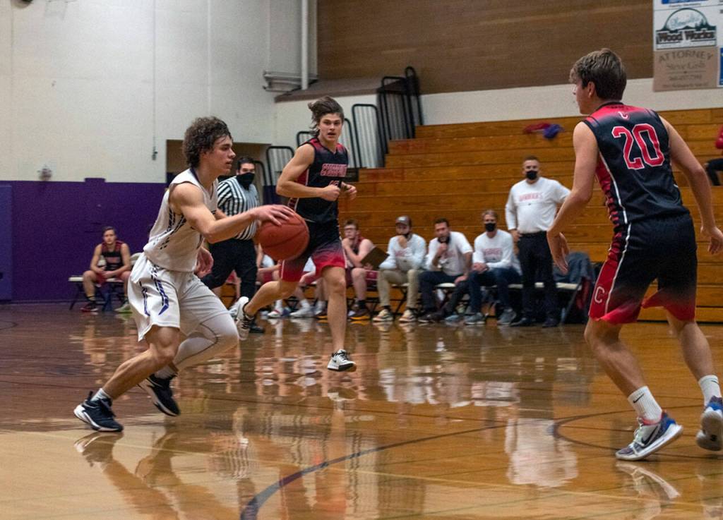 As Sequim guard Tyler Mooney, left, brings the ball upcourt, Crosspoint Academy coach Darren Doty (background, standing) looks on. Doty played for the Wolves, helping lead Sequim to its lone state championship game appearance against Rainier Beach in 1988. Sequim Gazette photo by Emily Matthiessen