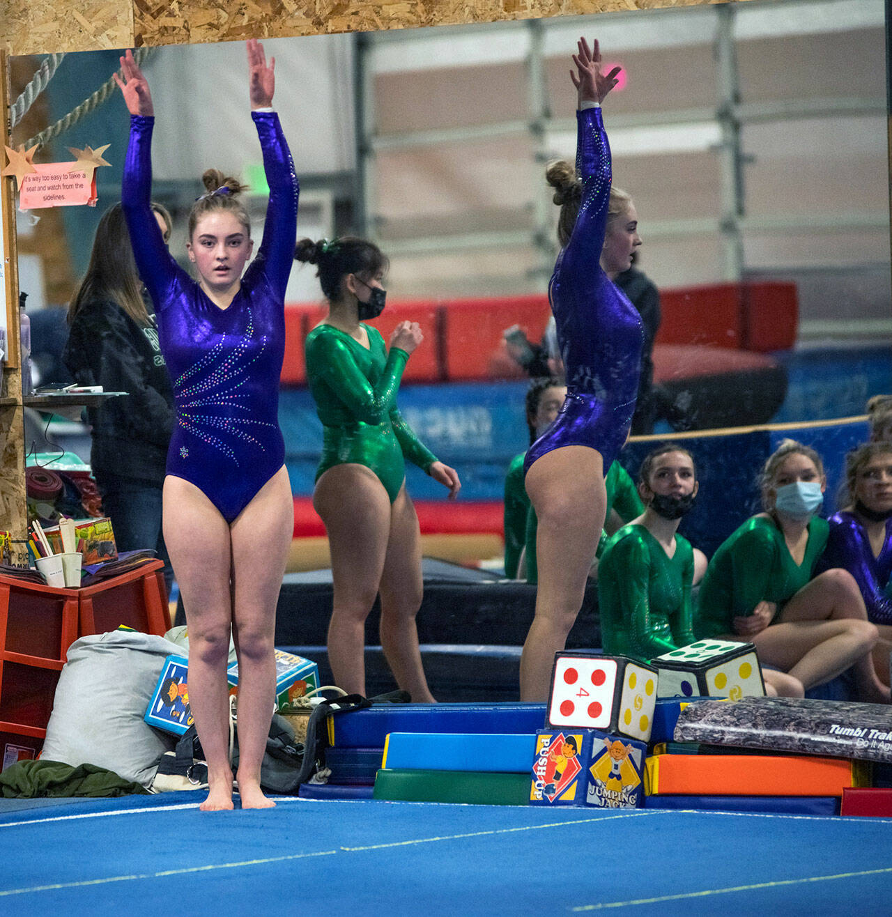As teammates look on, Sequims Alex Schmadeke competes in the floor exercise in a league meet on Jan. 19 in Port Angeles.