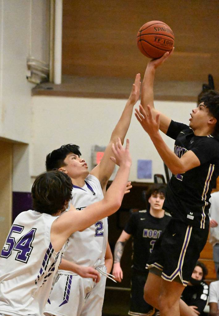 Sequim guard Kristian Mingoy, center, tries to block the shot of North Kitsap guard Harry Davies in a Jan. 20 Olympic League match-up in Sequim. North Kitsap won, 78-40. Sequim Gazette photo by Michael Dashiell