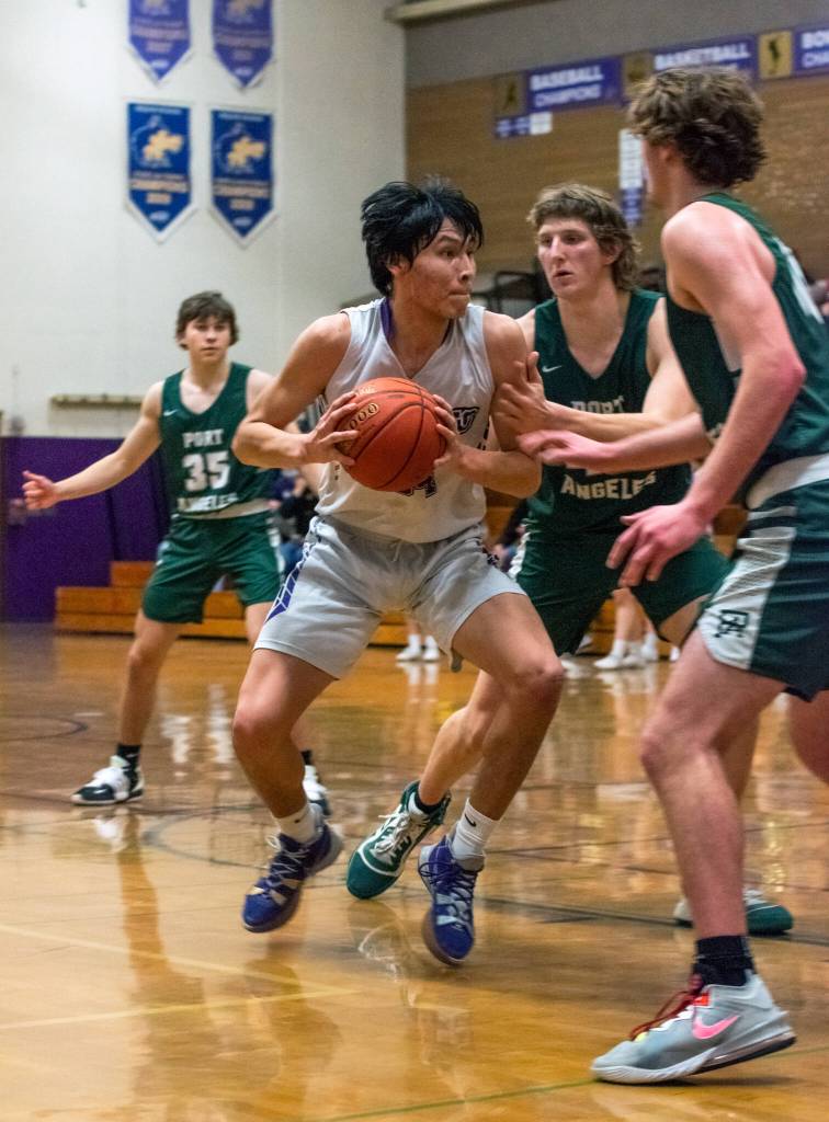 Sequims Isaac Moore, center, looks for room to put up a shot in the Wolves 62-49 loss on Feb. 3. Sequim Gazette photo by Emily Matthiessen