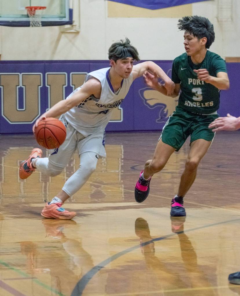 Sequim guard Jayden Possin, left, drives past Port Angeles Quanah Wheeler in a Feb. 3 Olympic League match-up. Sequim Gazette photo by Emily Matthiessen