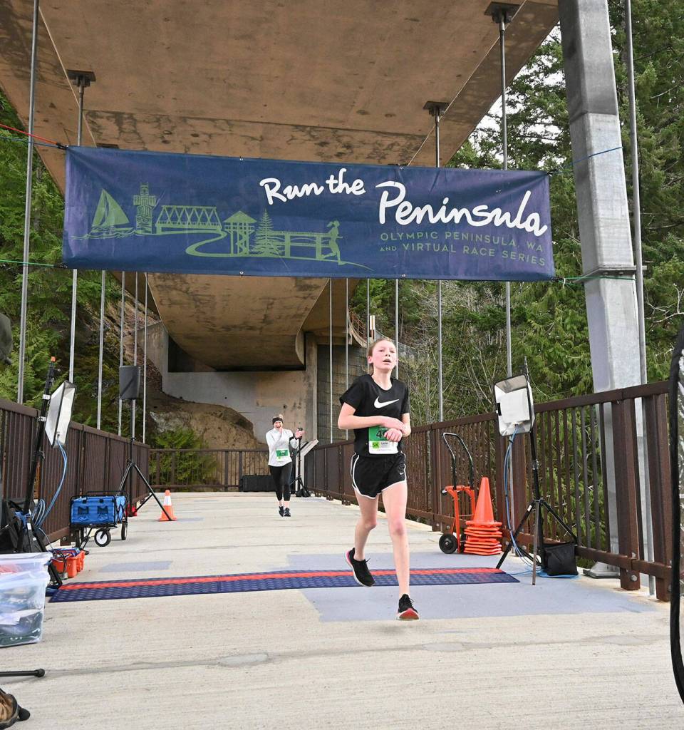 Shannon Newman, background, cheers on 13-year-old Leia Larson of Port Angeles in the Elwha Bridge run on Feb. 5. Larson (21:57) edged Newman by just one second. Sequim Gazette photo by Michael Dashiell