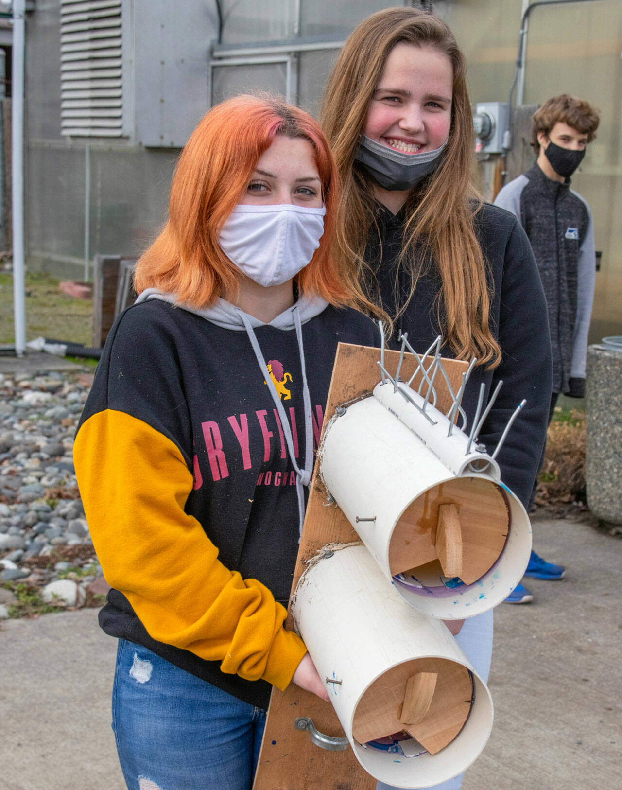 Shasta Larson and Addison Loewen, two of 52 Sequim High School students who built purple martin nesting boxes, hold up a finished piece with space for two purple martin families. Sequim Gazette photo by Emily Matthiessen