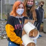 Shasta Larson and Addison Loewen, two of 52 Sequim High School students who built purple martin nesting boxes, hold up a finished piece with space for two purple martin families. Sequim Gazette photo by Emily Matthiessen