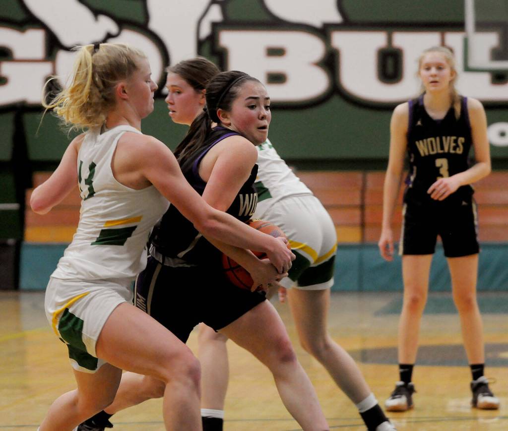 Sequim guard Hannah Bates, center, muscles her way into the lane looking for a basket in the Wolves state regional playoff game against Lynden on Feb. 25. Sequim Gazette photo by Michael Dashiell