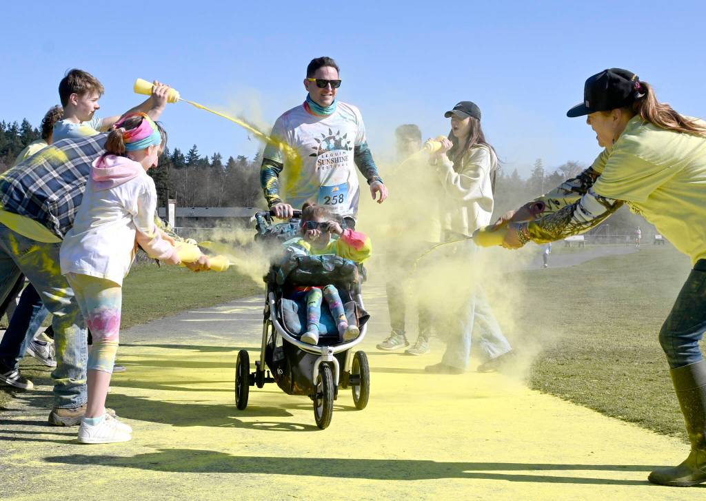 Cade Moses of Port Angeles and (almost) 5-year-old Cameryn enjoy a splash of yellow at the last color station at the Sun Fun Color Run 5k Saturday morning at the Albert Haller Playfields just north of Carrie Blake Community Park. More than 500 participants were registered to run/walk 5k and 1k race. Sequim Gazette photo by Michael Dashiell