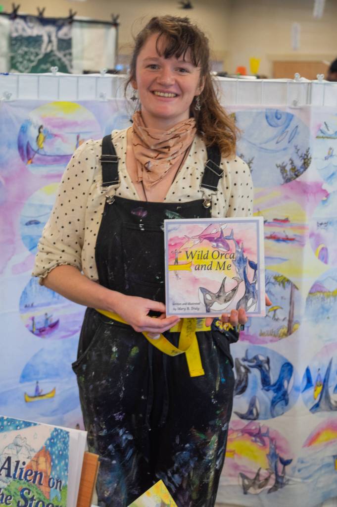 Louanne Linder, John Riley and Linda Alders, volunteers at the Sequim Valley Lions food stand, raise money for the clubs general fund at the Sequim Sunshine Festival Market on March 5. Sequim Gazette photo by Emily Matthiessen
Artist and author Mary B. Truly displays one of her publications at the Sunshine Market on Saturday. (For more about the artist/author, see marybtruly.com). Sequim Gazette photo by Emily Matthiessen