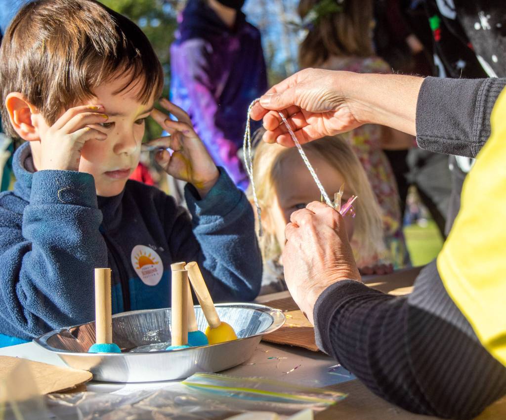 Five-year-old Jordan Dix watches intently as a volunteer demonstrates how to put together a sun luminary at the Let Your Little Light Shine Luminary Workshop during Sequims third annual Sunshine Festival. Sequim Gazette photo by Emily Matthiessen