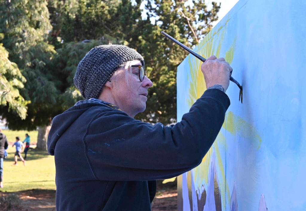 Sequim artist Craig Robinson refreshes this mural, updating it from last years message of Be the i in Sequim to Spectacular Sequim at Carrie Blake Community Park on March 5, as part of the 2022 Sequim Sunshine Festival. Sequim Gazette photo by Michael Dashiell