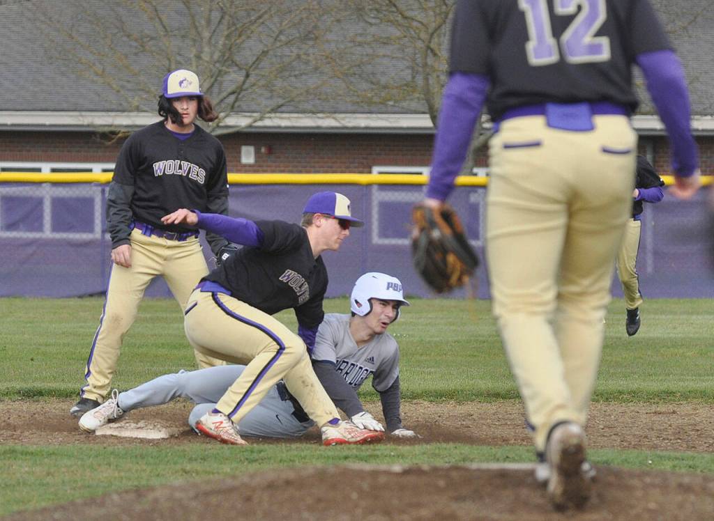 Sequim shortstop Conor Bear puts the tag on a Bainbridge runner in the first inning of the Wolves league match with with the Spartans on March 15. Teammates Jaxson Gray (foreground) and Marshall Phipps look on. Sequim Gazette photo by Michael Dashiell