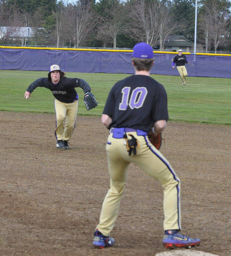 Sequim second baseman Marshall Phipps gathers up a grounder and throws to first baseman Zac McCracken to throw out a Bainbridge runner in a March 15 Olympic League game. Sequim Gazette photo by Michael Dashiell