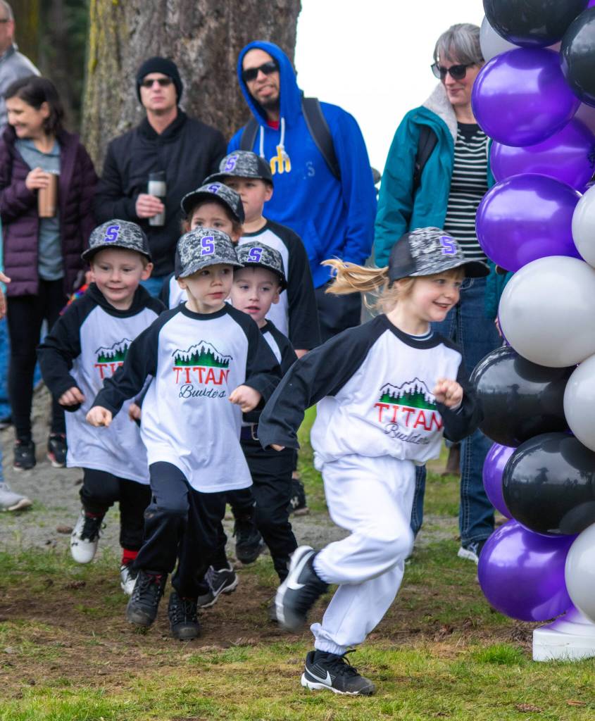 Titan Builders sponsored team rushes into the Don Knapp Field on Saturday during Sequim Little Leagues opening ceremony of the 2022 season.