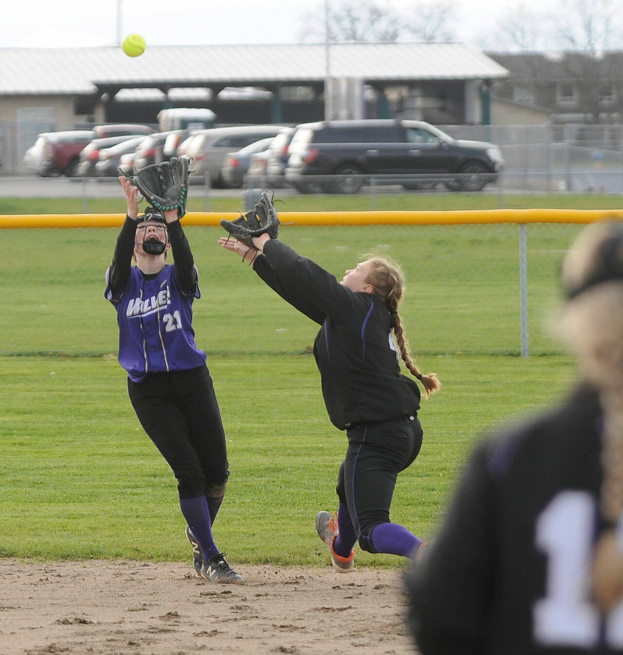 Sequim shortstop Hannah Bates, left, snags an infield pop-up as second baseman Addie Smith backs her up in the Wolves 8-6 loss to North Kitsap on March 29.