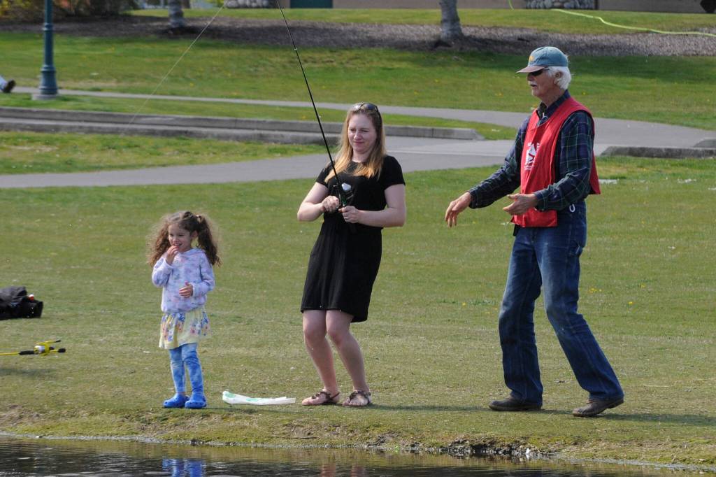 Sequim Gazette photos by Matthew Nash
Yuliya Berretta of Port Angeles helps her daughter Elise, 4, reel in a fish with advice from Barry Baker with the Puget Sound Anglers-North Olympic Peninsula Chapter. Hundreds of people gathered on April 23 for the clubs annual Kids Fishing Day in Carrie Blake Community Park.