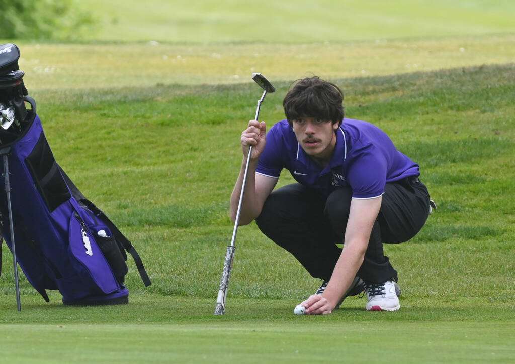 Sequims Cole Smithson lines up a putt on the green at the 11th hole in an April 28 Olympic League match against North Kitsap. Smithson made the shot and earned a birdie on the hole. Sequim Gazette photo by Michael Dashiell