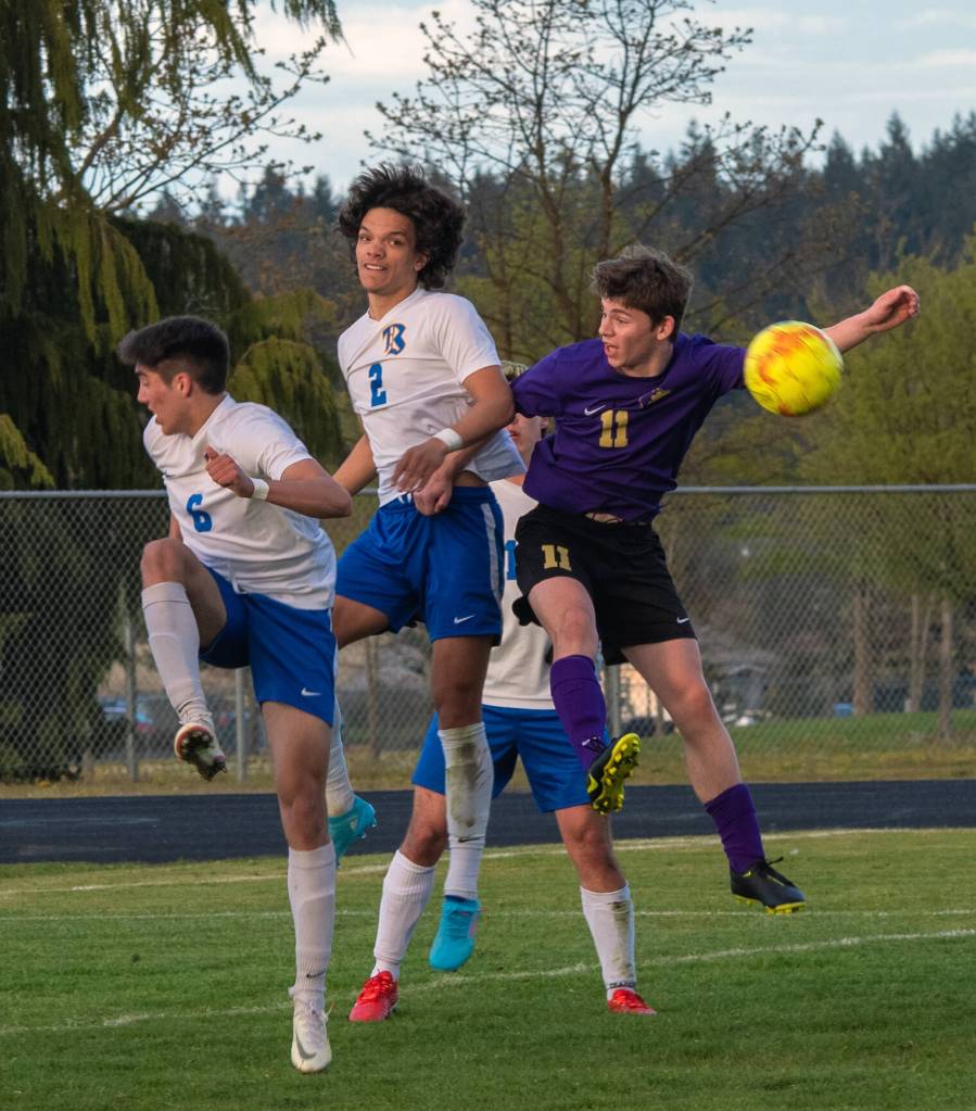 As Knights Aidan Harvey (2) and Diego Clemen (6) defend, Sequims Ethan Knight goes up for a header in the Wolves April 26 home league game against Bremerton. Sequim Gazette photo by Emily Matthiessen