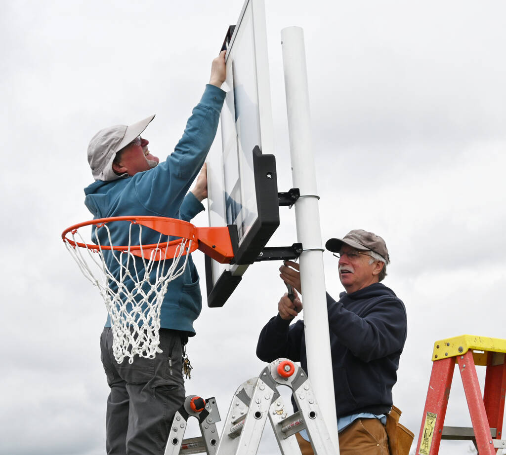 Steve Gilstrom, left, and Mark Holloway put up a basketball hoop at Helen Haller Elementary Schools playground on Beautiful Day, April 30.