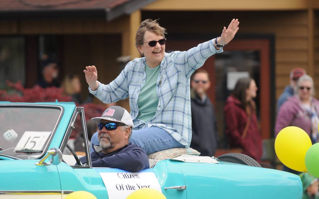 Michael Dashiell/Sequim Gazette
Jean Wyatt, the 2022 Sequim-Dungeness Valley Chamber of Commerces Citizen of the Year, waves to the crowd at Saturdays Grand Parade, hitching a ride with Paul McHugh.