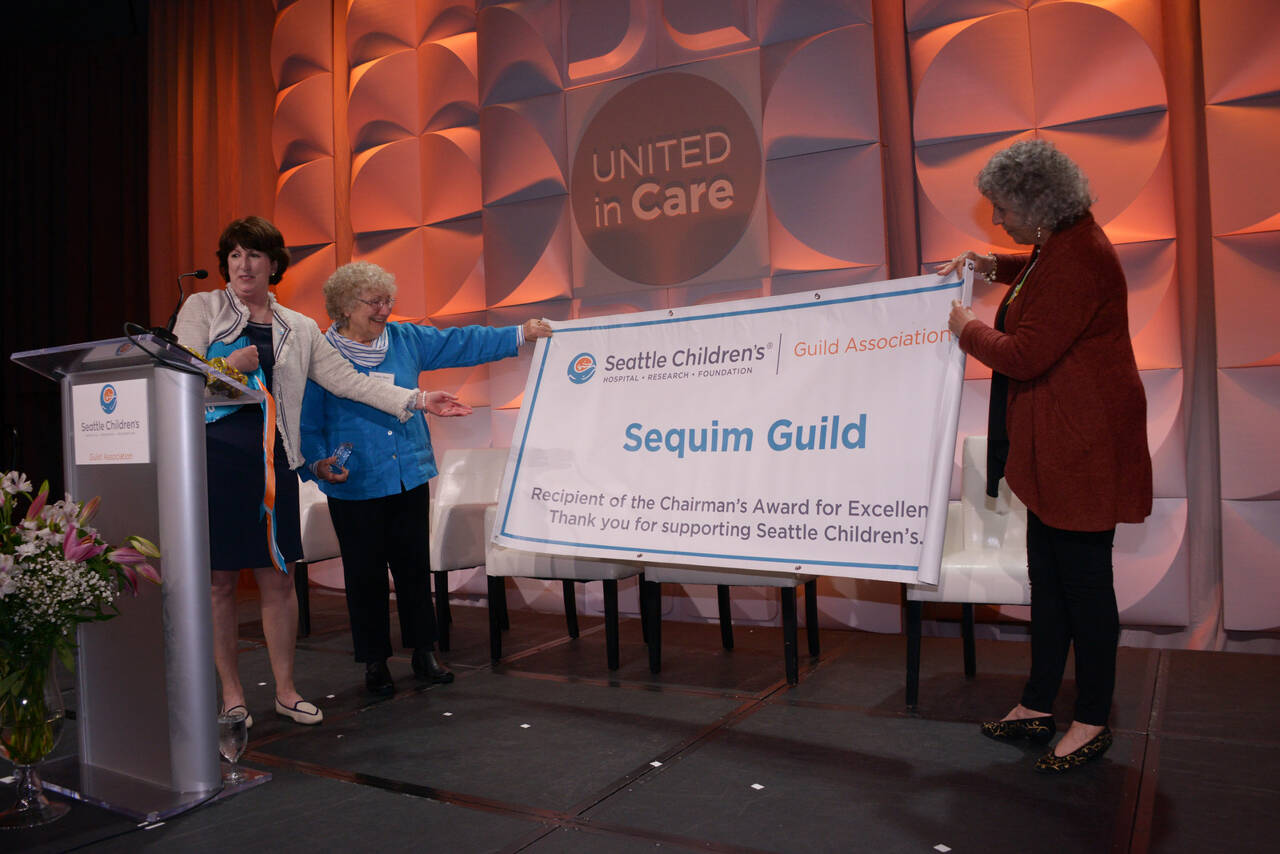 Submitted photo
Ann Shanahan, a trustee with the Seattle Childrens Guild Association, presents a banner displaying the Chairmans Award to Sequim Guild president Kathy Bare and secretary Lydia Stanhope at the Seattle Childrens Guild Association 2022 Annual Meeting & Luncheon on May 13.