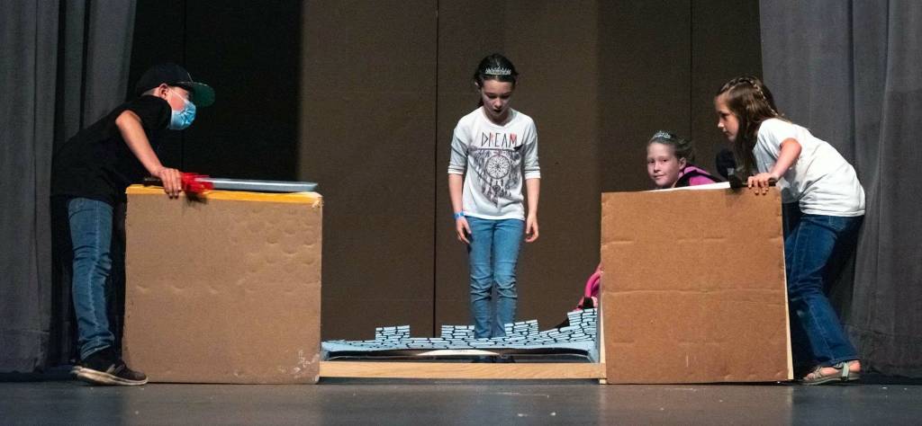 Rivers Maynard, Madelynn McIntyre, Sophia Mason and Brooklynn Glavin grapple with repairing the castle in Dragon Trouble, a play performed by 20 1st-5th graders from Olympic Peninsula Academy on June 3 and 4 at Sequim High School auditorium. Sequim Gazette photo by Emily Matthiessen